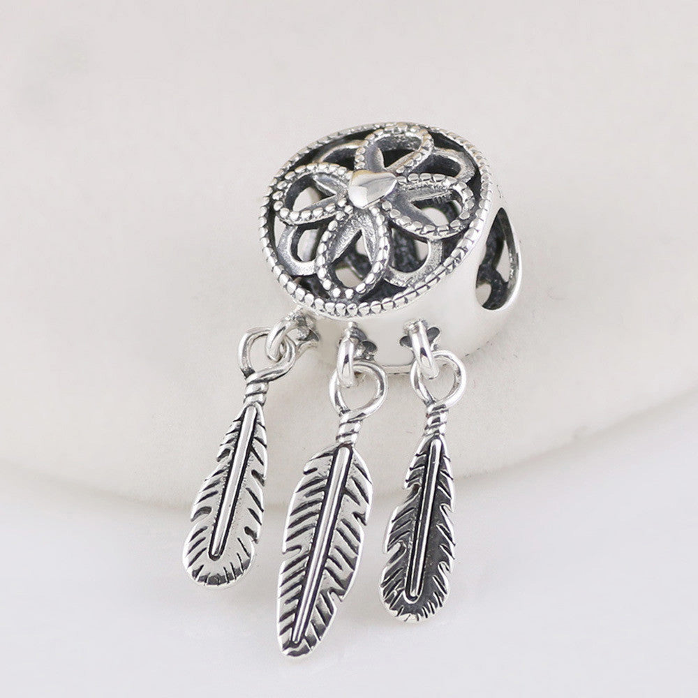 Silver dreamcatcher charm with feathers on a white background
