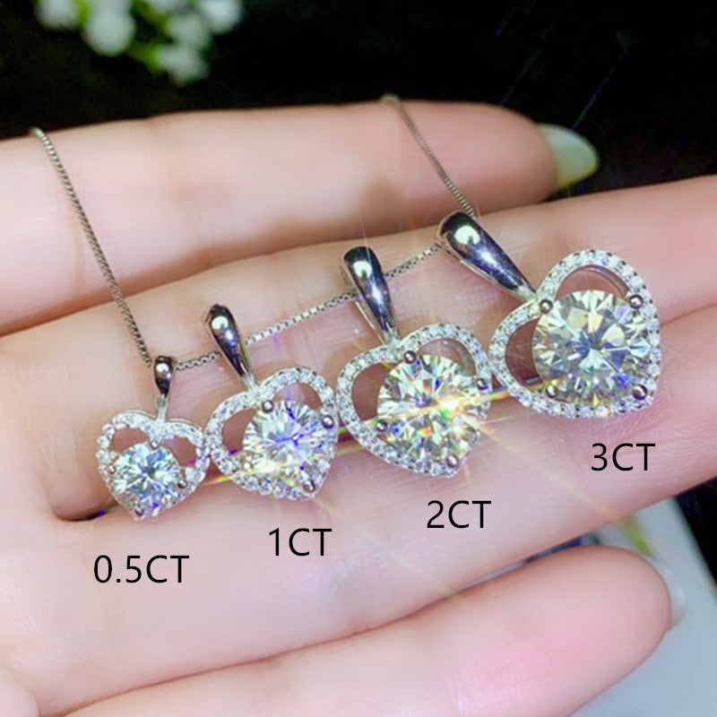 Heart-shaped diamond pendants on a hand with labeled carat weights.