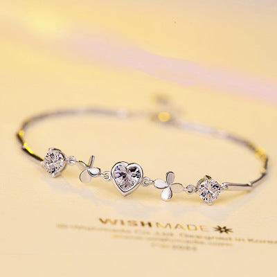 Silver bracelet with heart-shaped crystals on a yellow background