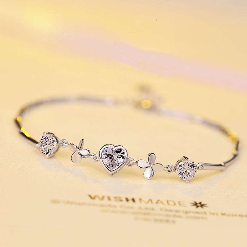 Silver bracelet with heart and leaf designs on a yellow background