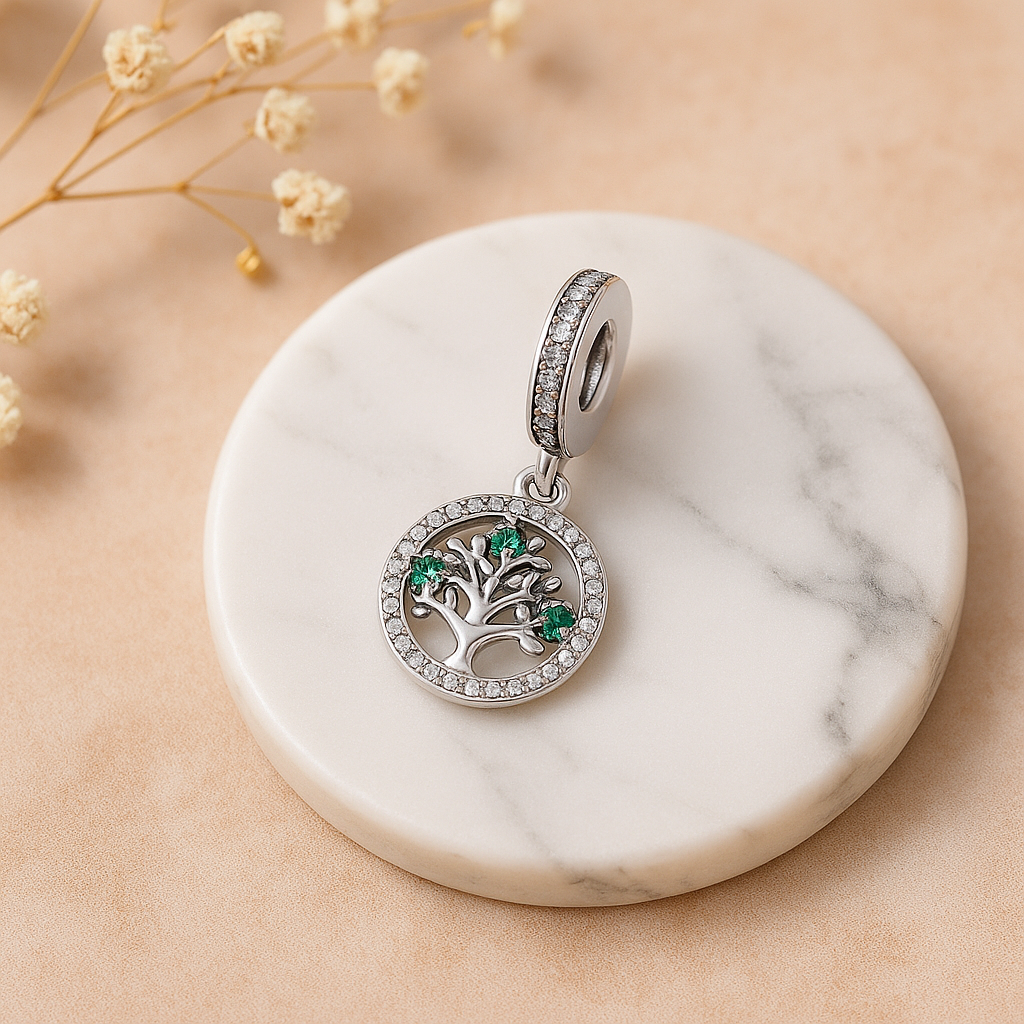 Silver pendant with green gemstones on a marble surface with dried flowers.