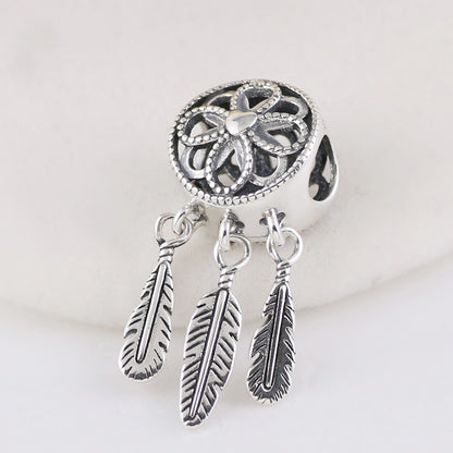 Silver dreamcatcher charm with feathers on a white background