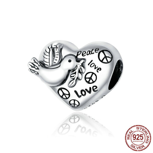 Silver heart-shaped charm with dove, peace signs, and 'Peace Love' text on a white background.