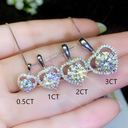 Heart-shaped diamond pendants on a hand with labeled carat weights.