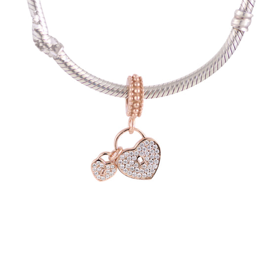 Silver snake chain necklace with a heart-shaped lock charm on a light pink background