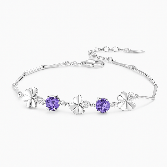 Silver bracelet with floral designs and purple gemstones on a white background